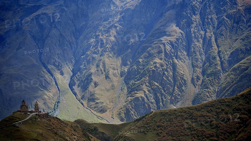 Picturesque mountain slopes with church on a hill in daylight, Gergeti Monastery, Georgia