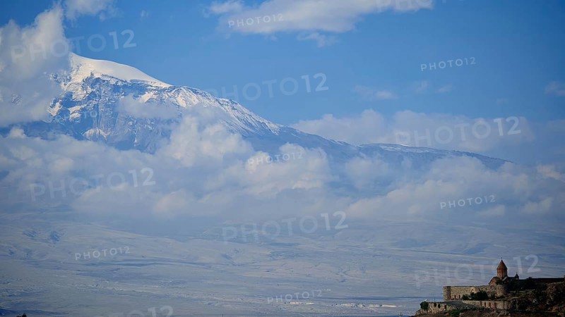 Snow-capped mountains and cloudy sky with a small monastery at the base, Khor Virap with Ararat in the background, Armenia