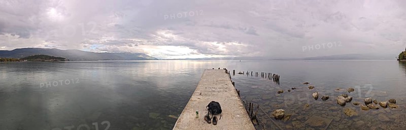 Long footbridge leads into a vast lake surrounded by peaceful countryside, Lake Ohrid, North Macedonia