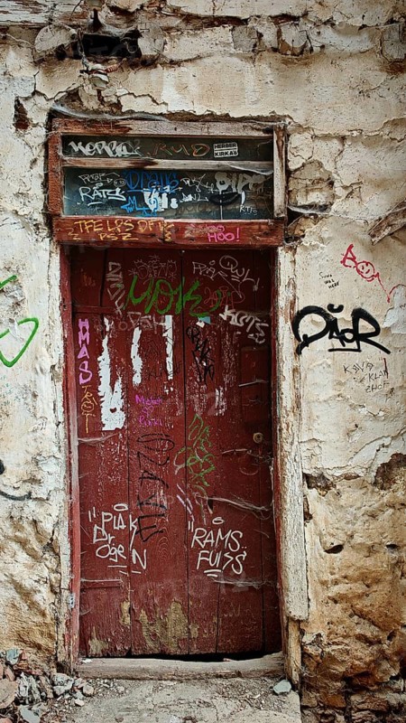 Old red door with graffiti in a weathered building, abandoned atmosphere, Ohrid, North Macedonia
