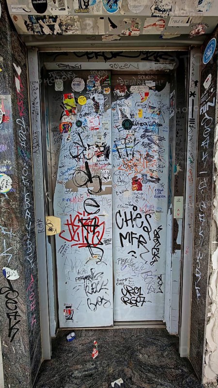 Elevator doors covered with graffiti and stickers in an urban setting, Prizren, Kosovo