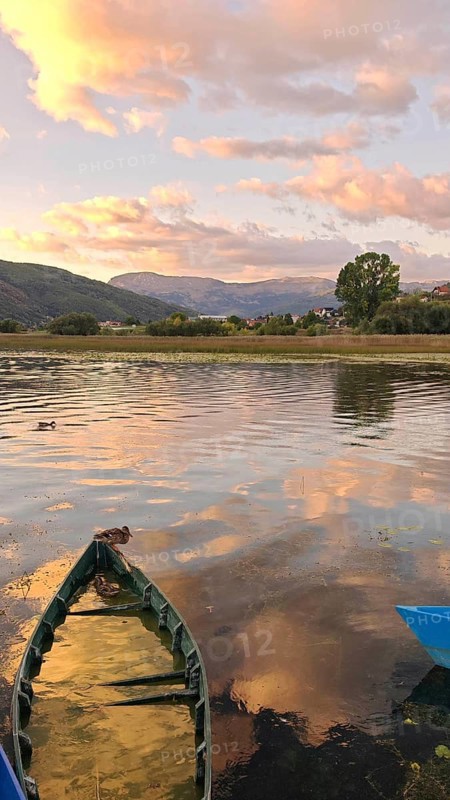 A lonely boat on a picturesque lake at sunset with mountain views, Plav Lake, Montenegro