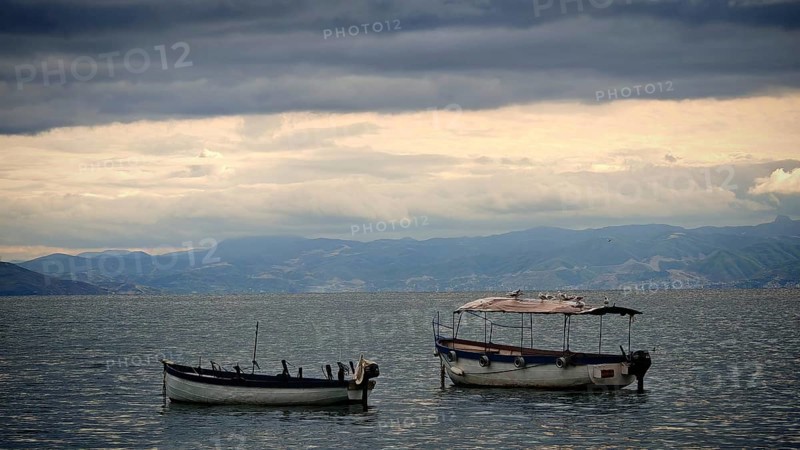 Two small boats float on a calm lake under a dramatic sky, Lake Ohrid, North Macedonia
