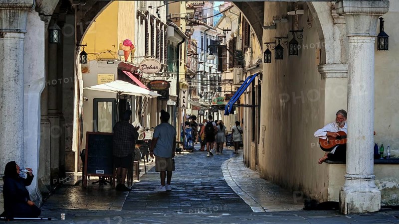 Bustling street with arcades, cafés and a seated musician, Slovenia