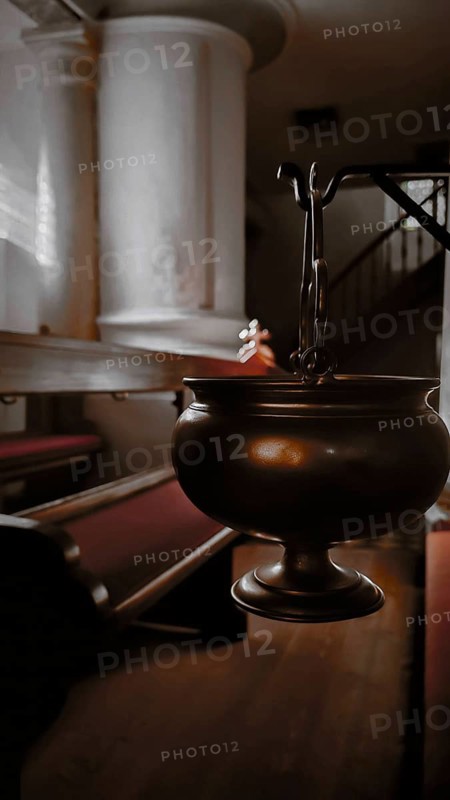 An incense barrel hangs in a quietly lit row of church benches, Frankenwald