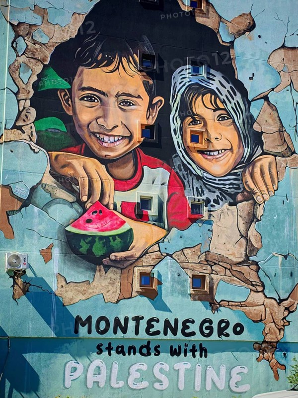 Wall painting of laughing children with text in support of Palestine