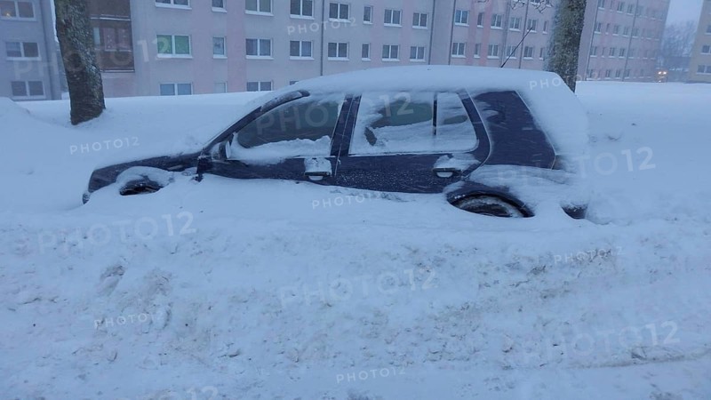 Snowy car parked in urban area after snowfall