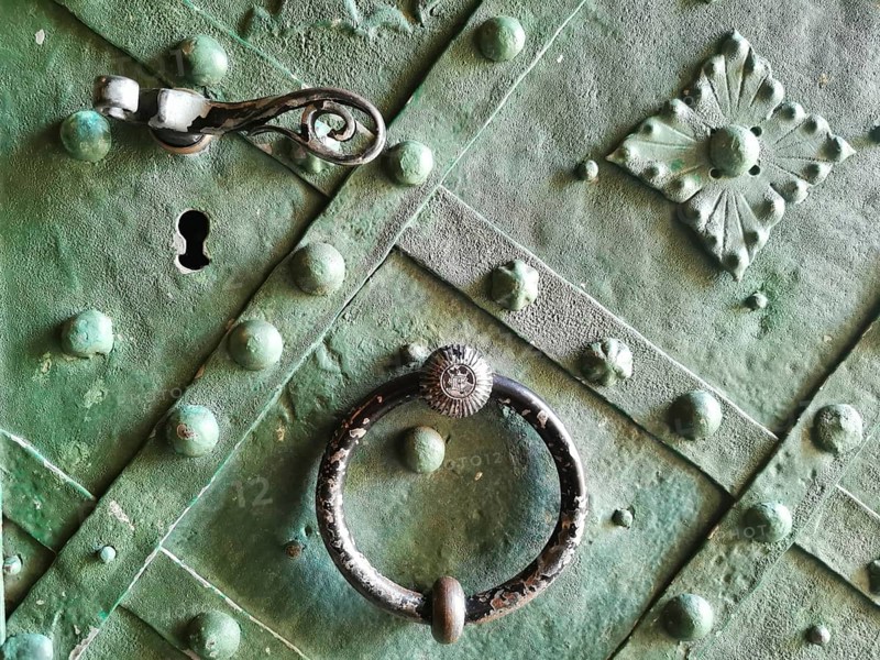Old green door section with decorative handle and metal ornaments
