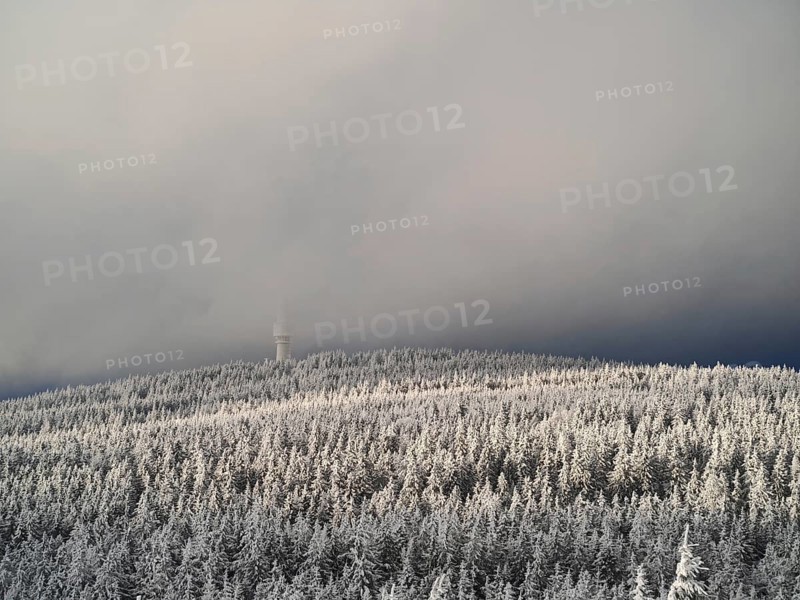 A snow-covered forest with a tower disappearing in fog on a hill, view from Nusshardt towards Bacöfele on the Schneeberg, Fichtelgebirge, Bavaria