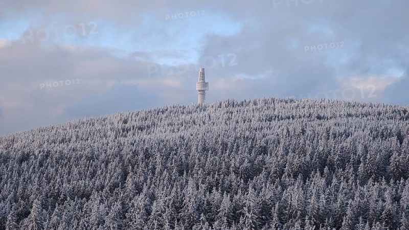 A snow-covered forest and a remote observation tower on a hill, view from Nusshardt towards Bacöfele on the Schneeberg, Fichtelgebirge, Bavaria