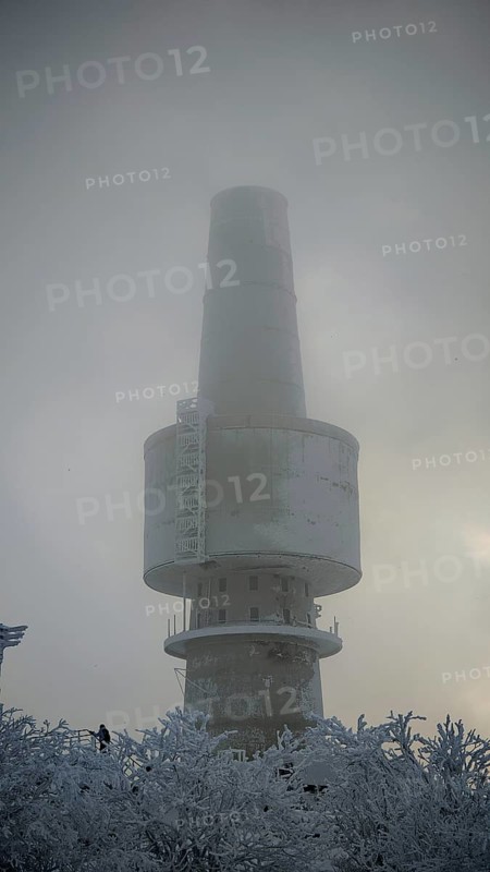 Mighty tower, surrounded by snow and fog, towering into the cloudy sky, Baköfele on the Schneeberg, Fichtelgebirge, Bavaria