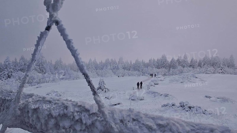 Snowy landscape with hikers and forest in the background. Twilight, quiet atmosphere, Schneeberg, Fichtelgebirge, Bavaria