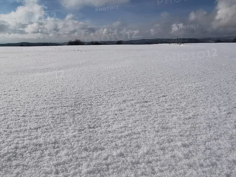 A vast snow-covered field under a blue sky with clouds, Franconian Forest