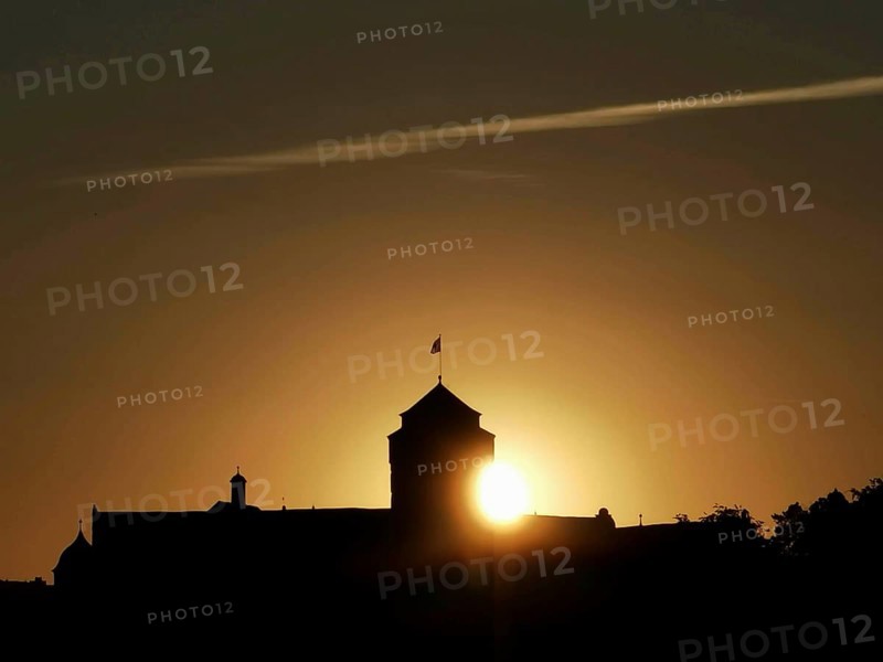Castle silhouette in front of a sunset with golden sun on the horizon