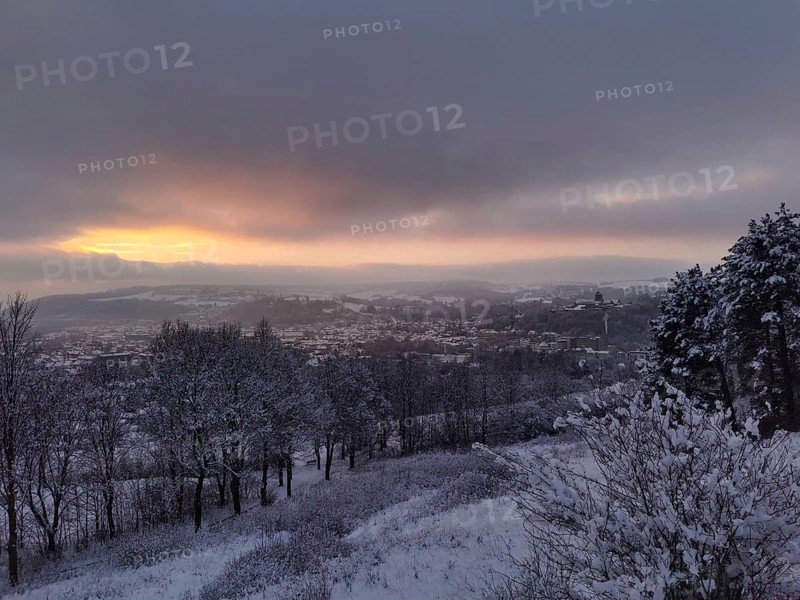 Snowy landscape with view of a village at sunset, view over Kronach in the Franconian Forest