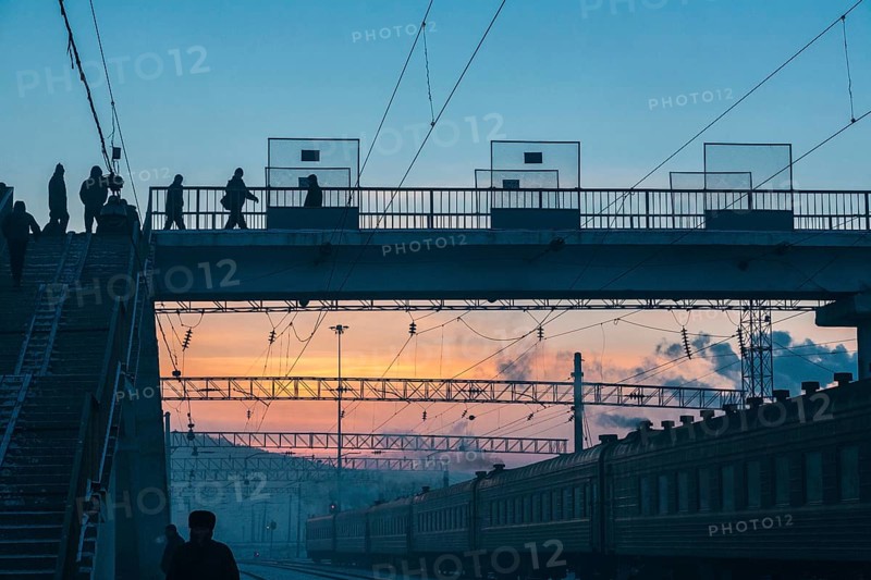 Siberia, Russia. People crossing a bridge at the train station near the Trans Siberian railway on its way to Moscow at dawn