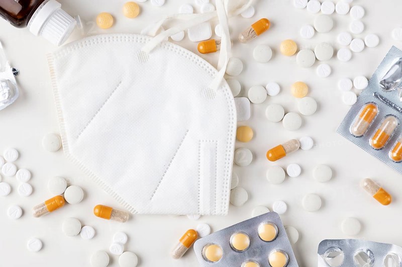 White respirator surrounded by scattered tablets and blister packs