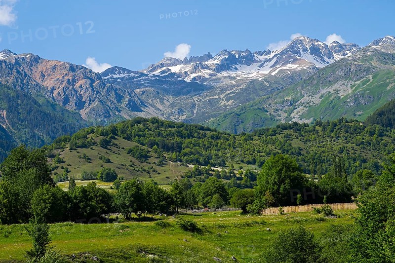 Mountain landscape with snow-capped peaks, green hills and a meadow under a clear sky, landscape near Iskari, Mingrelia and Upper Svaneti, Samegrelo-Zemo Svaneti, Svaneti, High or Greater Caucasus, Georgia