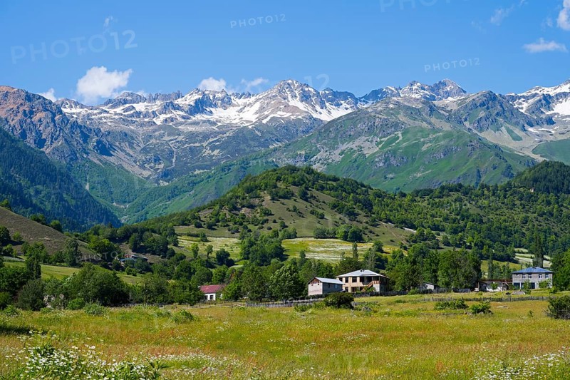 Picturesque mountain landscape with snowy peaks, green hills and meadows under blue skies, landscape near Iskari, Mingrelia and Upper Svaneti, Samegrelo-Zemo Svaneti, Svaneti, High or Greater Caucasus, Georgia