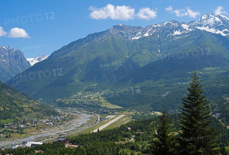 Valley with river and adjacent mountains under a bright blue sky, in the middle an airport, Mestia, Mingrelia and Upper Svaneti, Svaneti, High Caucasus, Georgia