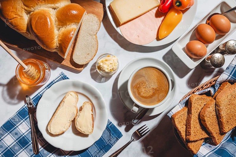 Breakfast with toast, sliced stollen, honey, cheese, ham, coffee, butter, bell pepper and eggs