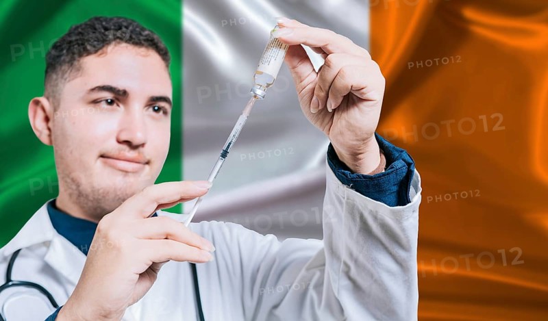 Doctor holding syringe on Ireland flag background. Medical professional holding syringe with Irish flag in the background