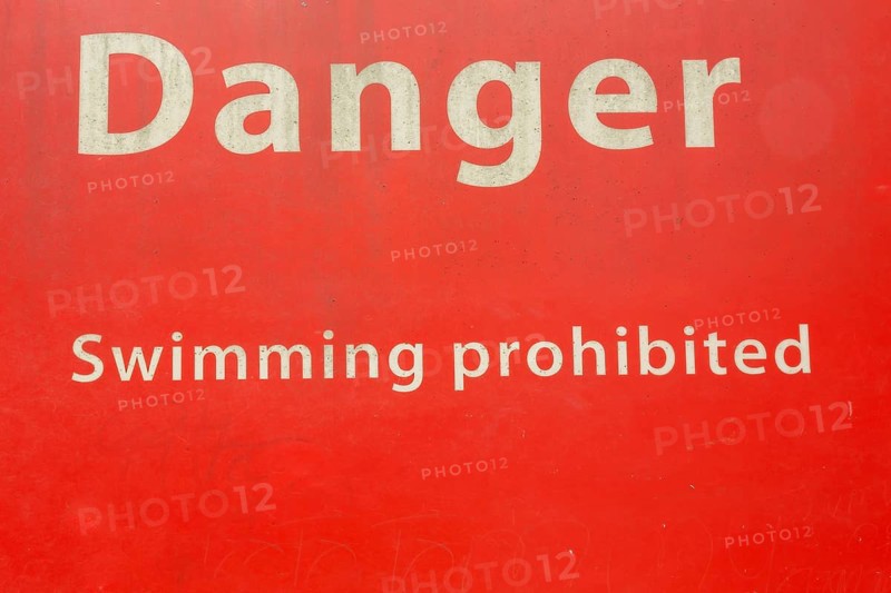 Danger Swimming Prohibited in white letters on red painted metal public notice sign in public park, Quebec, Canada
