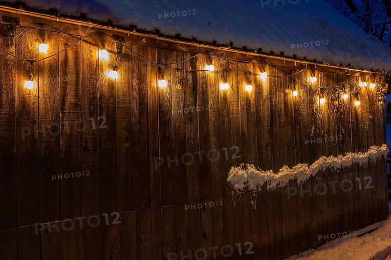 Illuminated old weathered wood plank cladded barn decorated with old industrial style string lights at night, Ile des Moulins, Old Terrebonne, Quebec, Canada