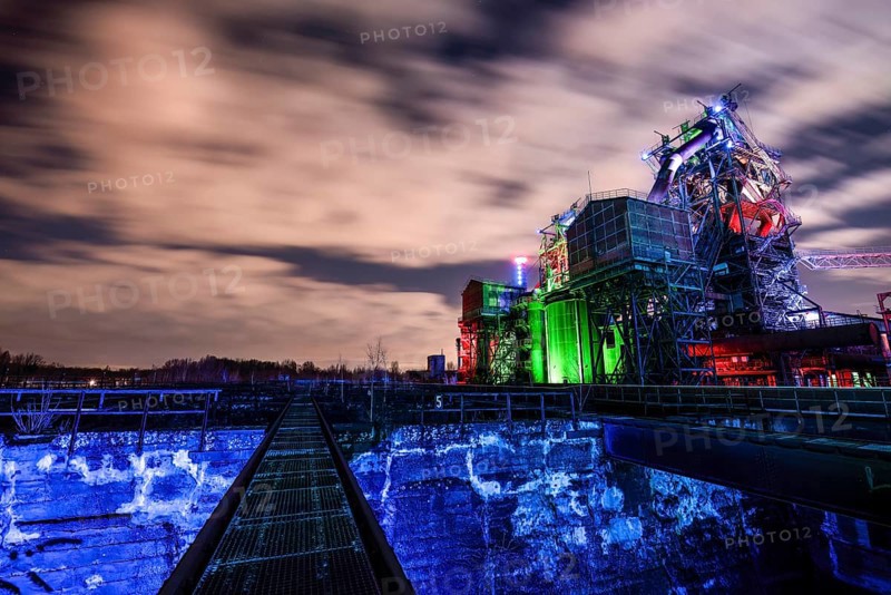 Night view of an illuminated industrial complex with dramatic cloudy sky, Duisburg Nord Landscape Park, Duisburg, North Rhine-Westphalia, Germany