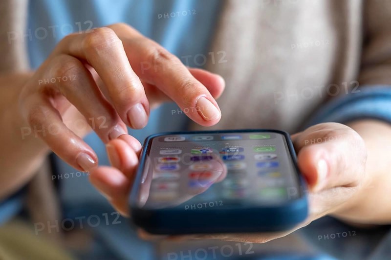 Mobile phone, in a user's hand, screen with various apps