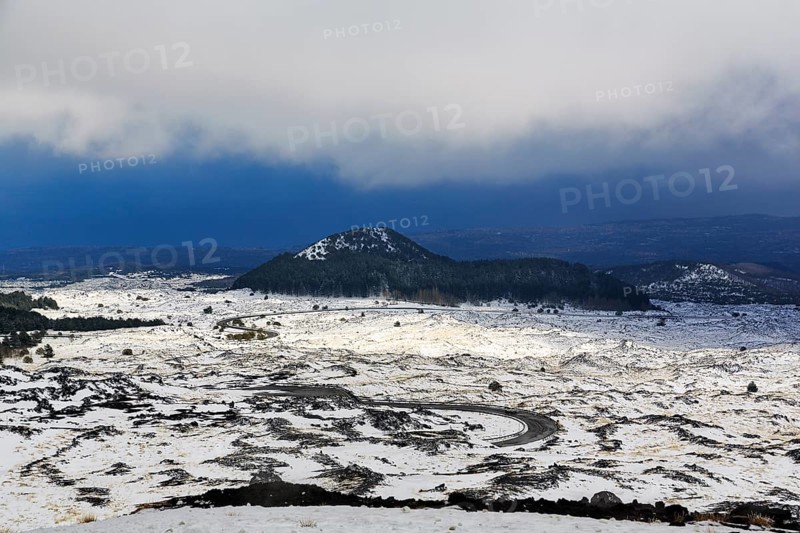 Wide, rugged lava field with volcanic cones, snow debris, curved road, Etna, Etna, Catania, Sicily, Italy
