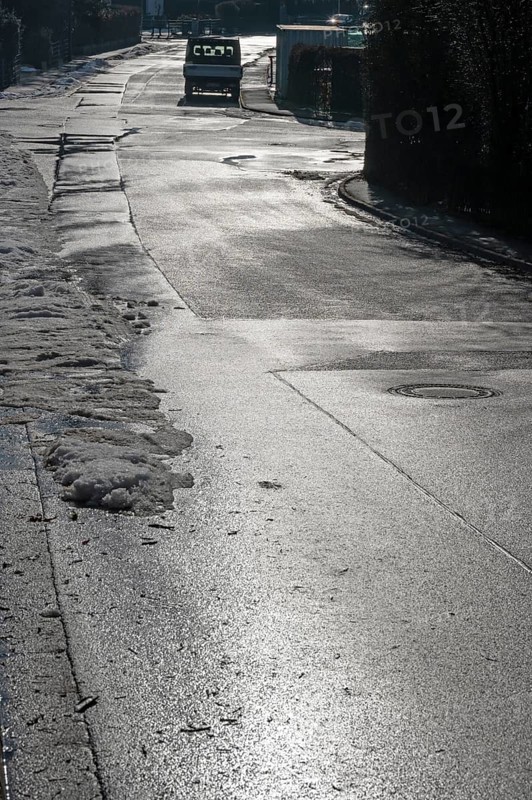Remains of snow on rain-wet road against light, Eckental, Middle Franconia, Bavaria, Germany