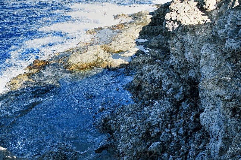 Coast with rocky cliffs and rough sea in bright sunlight, Playa Blanca Lanzarote