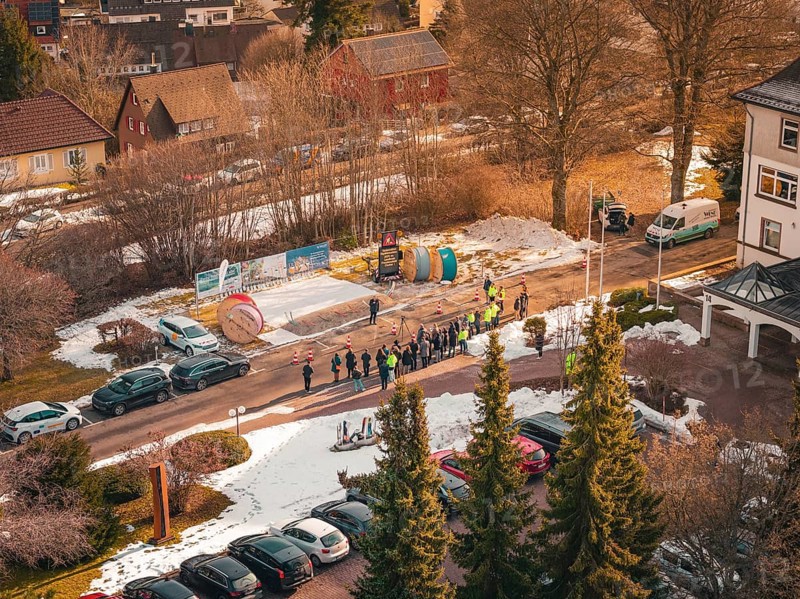 Aerial view of a crowd of people next to cable drums on a snowy road, fiberglass groundbreaking, Freudenstadt, Germany