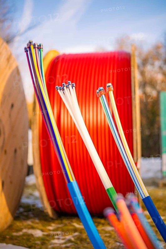 Colourful cables in front of large, red cable spools in a winter environment, fibre-optic groundbreaking, Freudenstadt, Germany