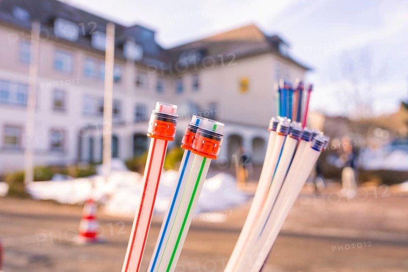 Colourful bundles of cables in front of a snow-covered building with people, fibreglass groundbreaking, Freudenstadt, Germany