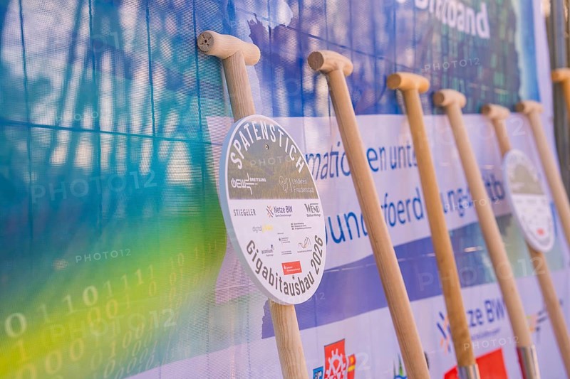 Row of shovels in front of an information poster at a symbolic event, fiberglass groundbreaking, Freudenstadt, Germany
