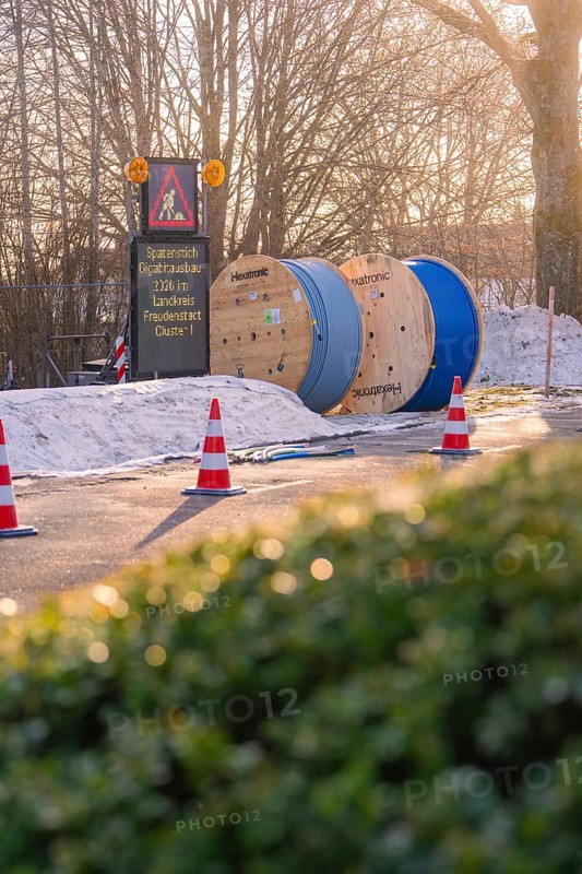 Cable drums and traffic cones on a construction site in the snow at sunrise, fibreglass groundbreaking, Freudenstadt, Germany