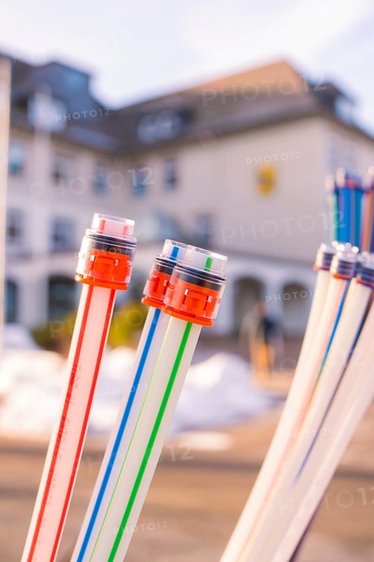 Colourful cables with coloured connectors in front of a blurred building, fibre-optic groundbreaking, Freudenstadt, Germany