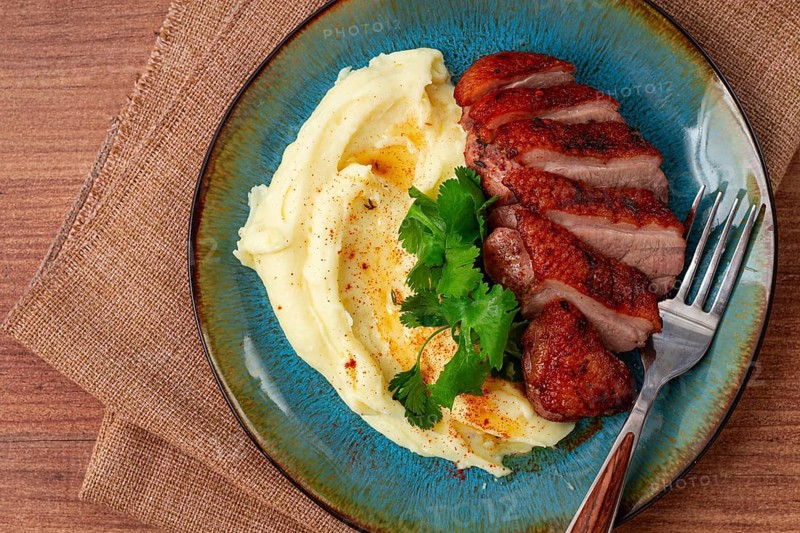 Roast duck breast, sliced with mashed potatoes, on a plate, close-up, no people