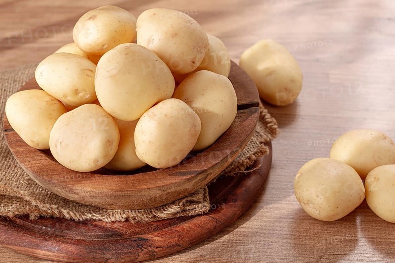 Boiled new potatoes, in a wooden bowl, on a rustic table, natural light, no people