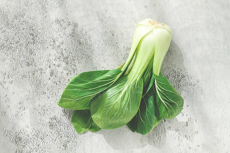 Fresh bok choy, laid out on a light gray surface, top view, natural light