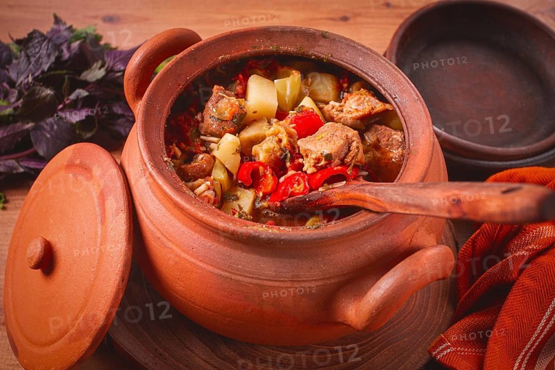 Chanakhi, a Georgian dish. in a clay pot, on a wooden table, stewed meat with vegetables, homemade, no people