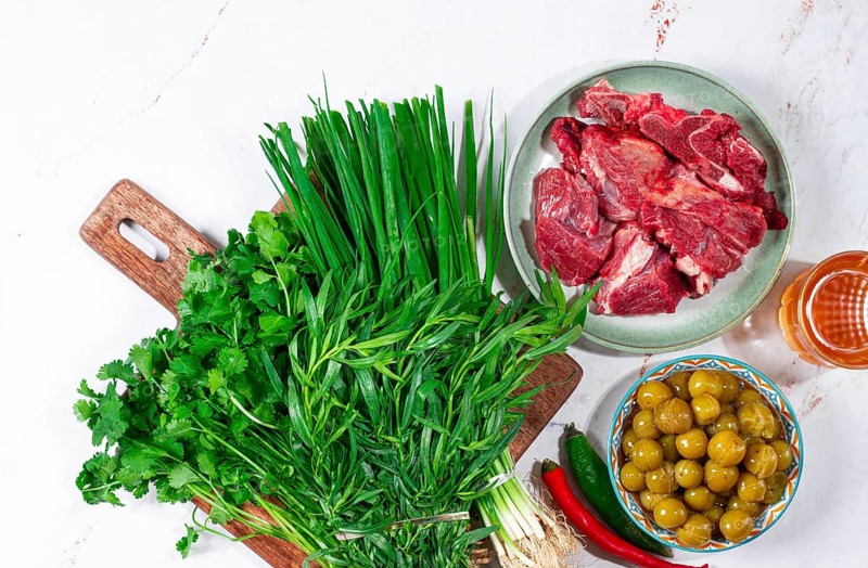 Ingredients for cooking chakapuli, canned tkemali, meat, herbs Georgian cuisine, top view