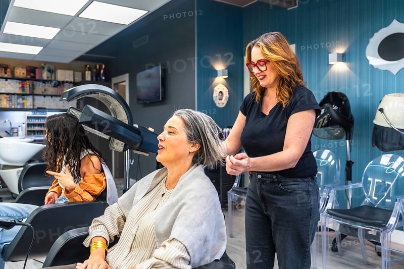 Professional hairdresser washing and styling a smiling mature womans gray hair in a modern salon, offering attentive hair care, pampering, and confident grooming service