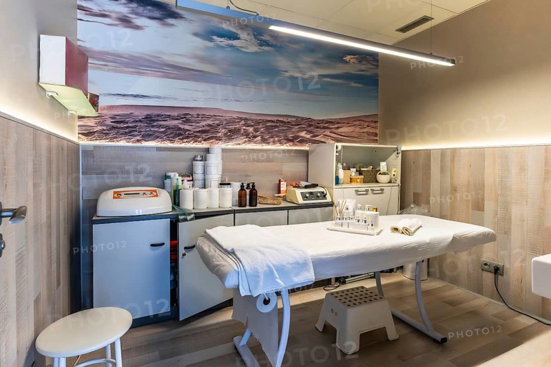 Professional beauty salon interior featuring a comfortable treatment bed, various skin care preparations, and modern aesthetic equipment, creating a serene environment for wellness