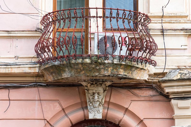 Rusted balcony grid with grotesque sculpture, Czernowicz, Ukraine