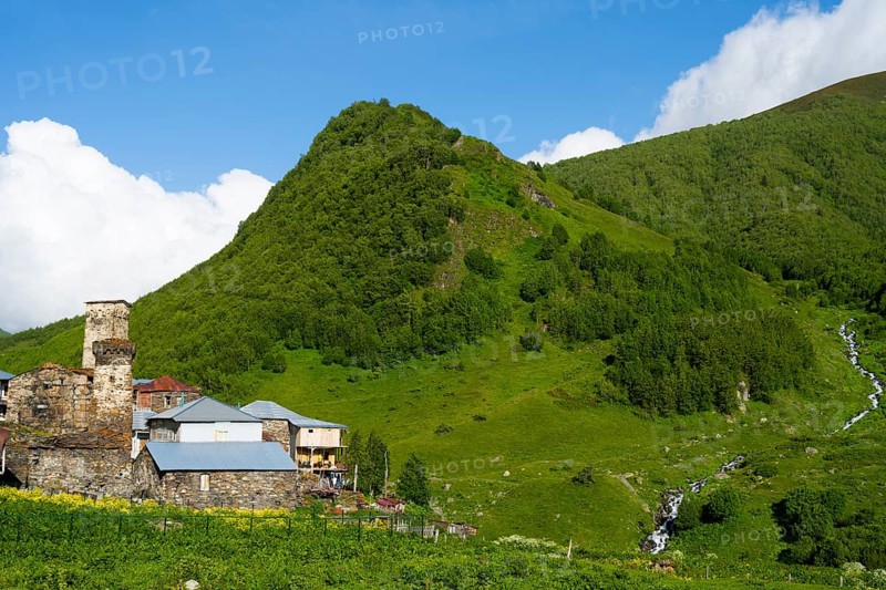 A green mountain with stone houses under a cloudy sky, defensive towers, Ushguli, Ushguli, Murqmeli district, Upper Svaneti, Svaneti, Georgia