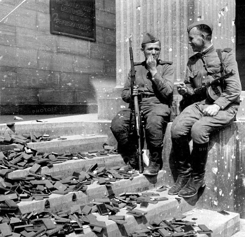 In front of the Reich Chancellery, Berlin in April 1945 J. Chaldej about this photo: The Reich Chancellery. These are medals that should be transported in boxes. The boxes were split in half, the crosses fell out. These two soldiers took a cigarette break in front of the Reich Chancellery