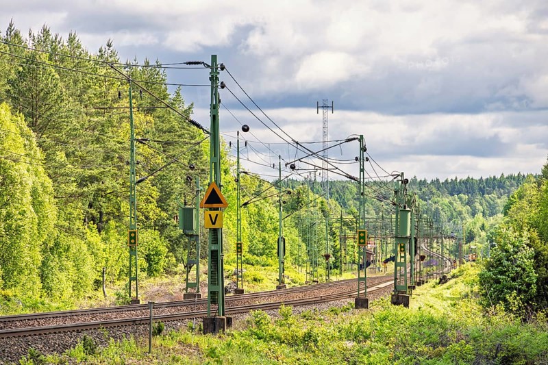 Electric railway line with overhead line in a deciduous forest in spring, Sweden